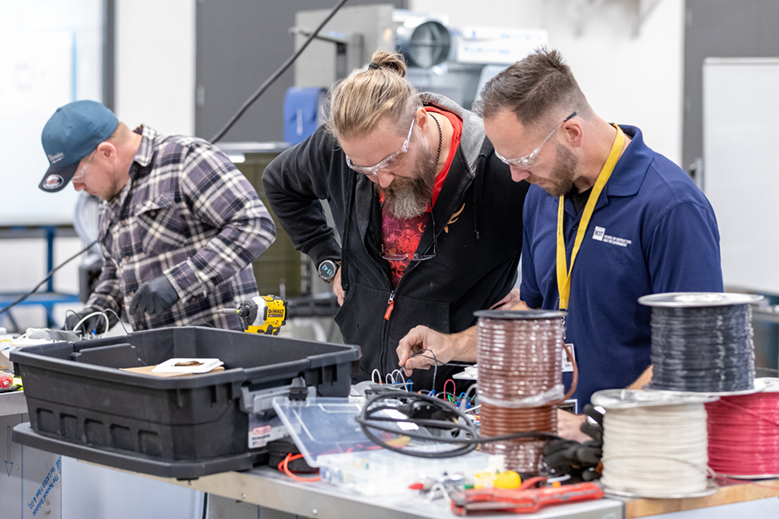 The instructor works with a student in the Residential Heat Pump training course while another student works in the background.