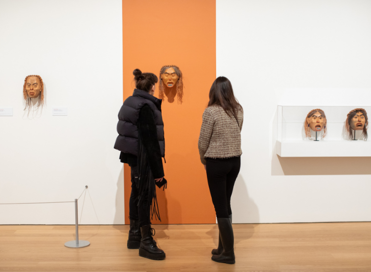 Attendees study a mask carved by Freda Diesing at the exhibition opening. 