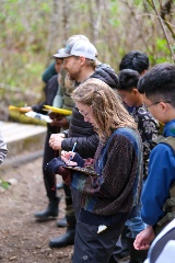 A student takes notes on a clipboard in the middle of a group.