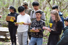 A group of students take notes in the wilderness during the field school.