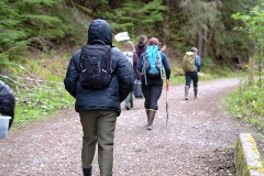 The class walks along a dirt road, facing away from the camera.