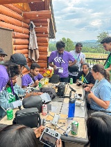 Students sit around a table, preparing drones for a birds-eye view.