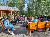 Field school students gather around a fire pit to discuss.